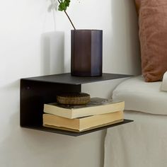 a black shelf with books and a vase on it