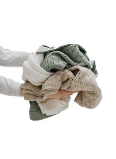 a woman's hands holding several folded clothes