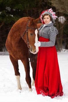 a woman standing next to a horse in the snow