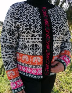 a woman wearing a black and white sweater with an orange, pink, and green design on it