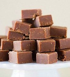 a pile of chocolate fudges sitting on top of a white cake plate