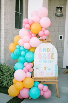 there is a sign that says ande babe is three on it with balloons in the shape of letters