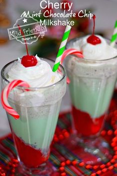 two glasses filled with whipped cream and candy canes on top of a red tray