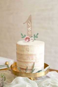 a white cake sitting on top of a gold platter with a pink frosting