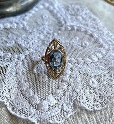 Featuring a gorgeous antique 1910s Edwardian Era solid 10k yellow gold decorative filigree statement ring adorned with a dazzling topaz blue marquee cut paste stone in a delicate bezel setting. Ring is approximately size 3.5 at 3.03 grams respectively and is stamped 10K on the inside of band.  This beauty is in excellent antique condition with paste stone intact with normal wear.  I have such an affinity for yellow gold blue together, this a beautifully crafted piece, ready to wear, size up and pass down for generations. Please feel free to contact me with any questions or suggestions I'm always learning  (Box not included) Bezel Setting Ring, Sketches Simple, Edwardian Era, Gold Filigree, Art Drawings Sketches Simple, Bezel Setting, Statement Ring, Rings Statement, Statement Rings