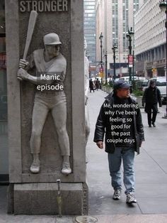 a man standing next to a statue of a baseball player on the side of a street