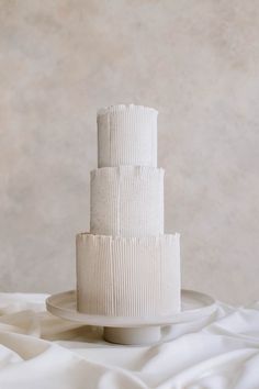 a three tiered white cake sitting on top of a plate