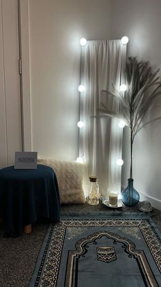 a room with a rug, table and lights on the wall next to a bed