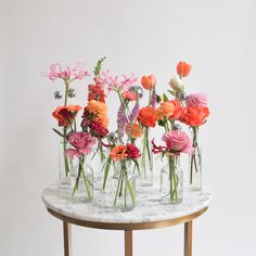 there are many vases with flowers in them on the marble table and white wall