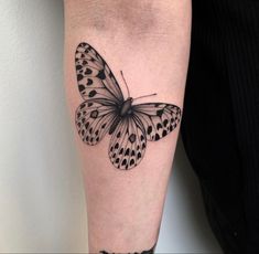 a black and white butterfly tattoo on the right arm, with dots all over it