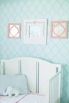 a baby's room decorated in pastel colors with pink and blue wallpaper