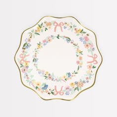 a white plate with floral designs and gold trimmings on the rim, decorated with scissors