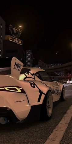 a white race car driving down a street at night