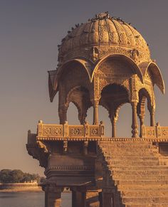 an ornate gazebo with steps leading up to it and a body of water in the background