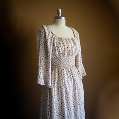 a white dress with red polka dots on it sitting on a mannequin head