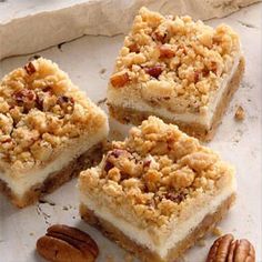 four pieces of cake sitting on top of a white plate with pecans around it