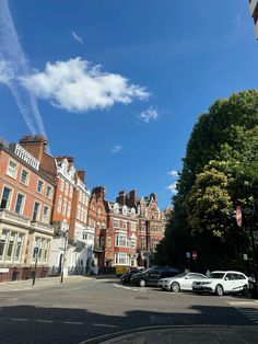 several cars parked on the side of an empty street in front of tall brick buildings