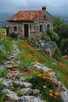 an old stone house sitting on top of a hill with flowers growing out of it