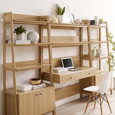 a wooden desk with a laptop on top of it next to a ladder shelf filled with books