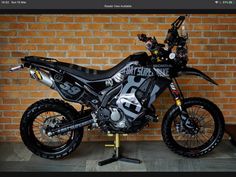 a dirt bike sitting on top of a stand in front of a brick wall,