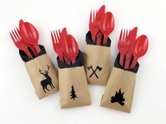 four red plastic forks and spoons in a brown paper bag with deer designs on it