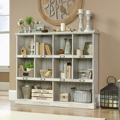 a white bookcase filled with lots of books on top of a hard wood floor