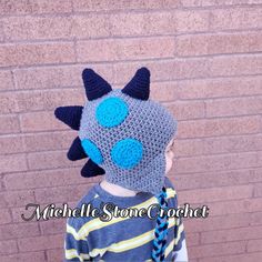 a young boy wearing a crocheted hat with blue eyes and horns on it