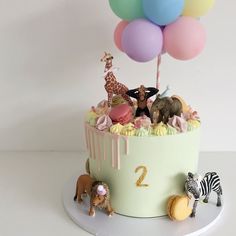 a birthday cake with animals and balloons on the top is decorated in pastel colors