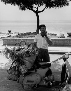 a man standing next to a scooter with baskets on the back of it