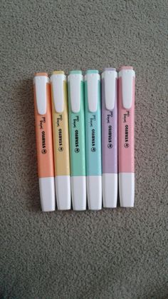 four pens are lined up next to each other on the floor, with different colors