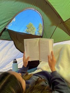 a person laying in a tent reading a book