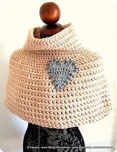 a crocheted shawl with a heart on the front, and a wooden button in the middle