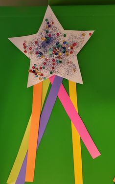 a star made out of colored paper on top of a green surface with streamers