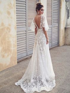 a woman in a wedding dress standing next to a building with shutters on it