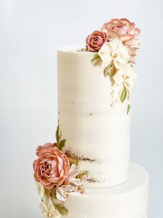 a three tiered white cake with flowers on top