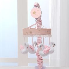 a pink baby crib mobile with two white swans hanging from it's sides