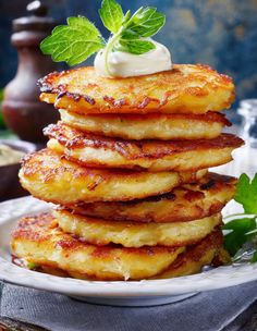 stack of pancakes topped with whipped cream and mint leaves on a plate next to a glass of milk