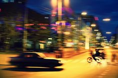 a blurry photo of cars and motorcycles on a city street at night with buildings in the background