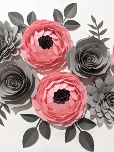 three paper flowers are arranged on a white surface