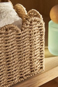 a wicker basket sitting on top of a wooden shelf next to a blue jar