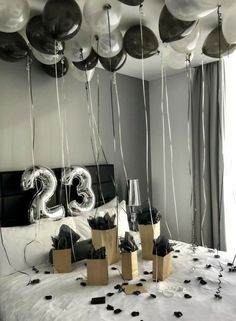 balloons are floating in the air above a bed with black and white decorations on it