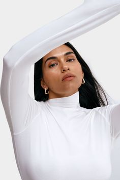 It’s our Ilana Top’s contemporary subtlety that makes her so outfit-changing. This long-sleeve top is crafted from soft, high-stretch and sustainable European jersey to mold perfectly and comfortably to your form. Her showpiece? The diagonal, raw-edged neckline, elevating a classic mock-neck design to a unique day-to-night essential. | Sejal, in off white, is 5'8" (173 cm) tall, wearing size M. Astrid, in off white, is 5'9" (175 cm) tall, wearing size XS. Yada, in mist, is 5'9" (175 cm) tall, we Long Sleeve Tops For Layering With Minimal Stretch, Long Sleeve Tops With Minimal Stretch For Layering, Long Sleeve Tops With Thumbholes, Long Sleeve Tops With Thumbholes And Minimal Stretch, Long Sleeve Top With Thumbholes And Minimal Stretch, Versatile Long Sleeve Mock Neck Top For Layering, Chic Fitted Top With Thumbholes, Fitted White Top With Thumbholes, Chic Fitted Tops With Thumbholes