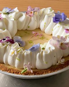 a cake with white frosting and purple flowers on it sitting on top of a table