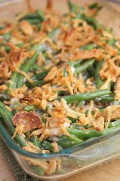 a casserole dish with green beans, onions and bacon in it on a wooden table