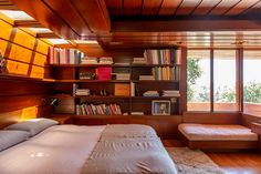 a bed sitting in a bedroom next to a book shelf filled with lots of books