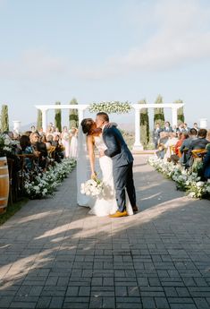 a bride and groom kissing in front of an outdoor ceremony