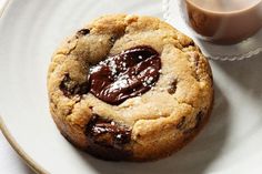 a chocolate chip cookie on a plate next to a cup of coffee