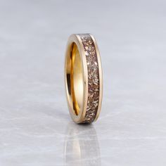 a gold wedding ring with brown and white glitter inlayed to the inside of it