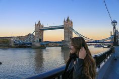 a woman is talking on her cell phone near the river thames in london, england