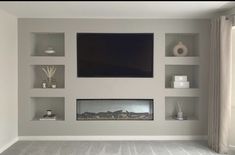 an empty living room with shelves and a flat screen tv mounted above the fire place